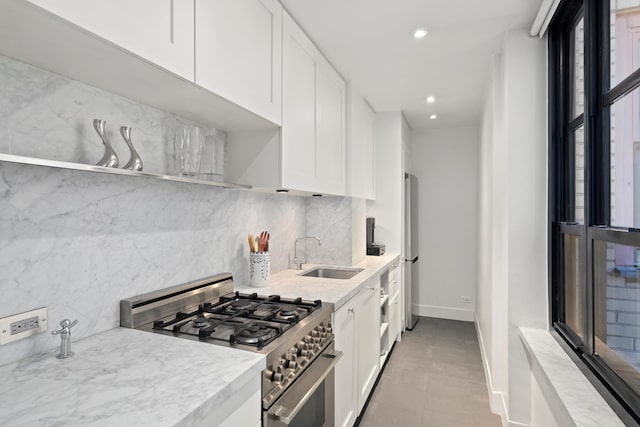 kitchen with light tile patterned floors, a sink, white cabinets, appliances with stainless steel finishes, and tasteful backsplash