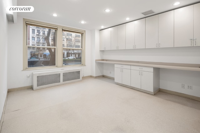 unfurnished office featuring radiator and built in desk