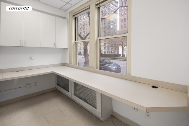 unfurnished office featuring a drop ceiling and built in desk