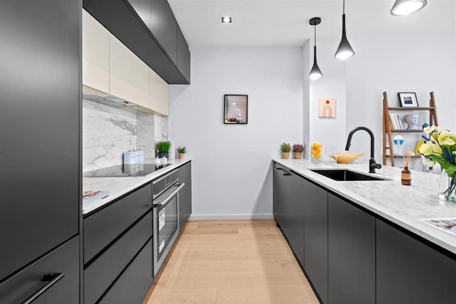 kitchen with decorative light fixtures, a sink, dark cabinets, oven, and black electric cooktop