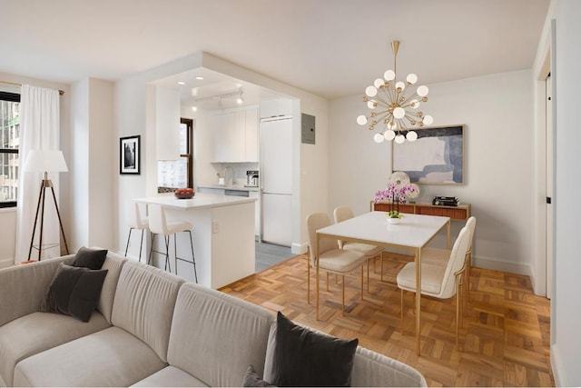 dining room with an inviting chandelier, rail lighting, and light parquet flooring