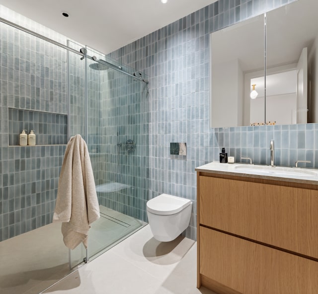 bathroom with toilet, vanity, tile walls, decorative backsplash, and an enclosed shower