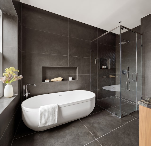 bathroom featuring plus walk in shower and tile walls