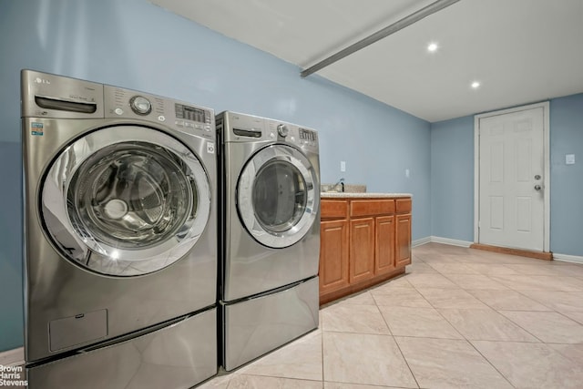 laundry area with cabinets, light tile patterned floors, and washing machine and clothes dryer