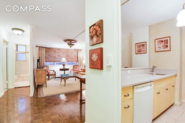 kitchen featuring light countertops, white dishwasher, and a sink