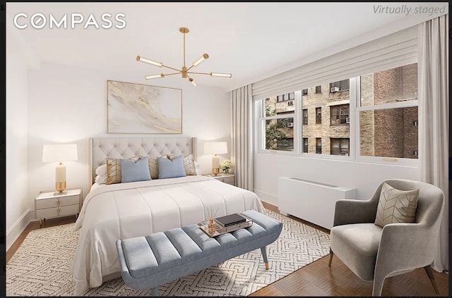 bedroom with a chandelier, radiator heating unit, baseboards, and wood finished floors