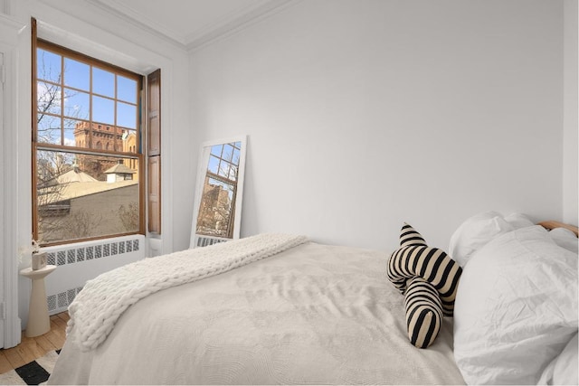 bedroom with ornamental molding, radiator, wood-type flooring, and multiple windows