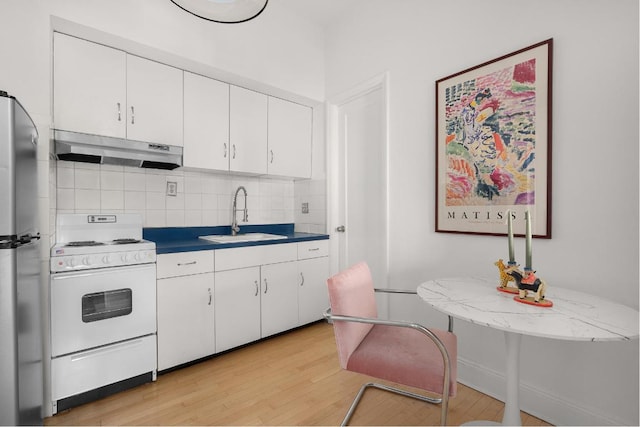 kitchen with white cabinetry, decorative backsplash, sink, white gas range oven, and stainless steel refrigerator