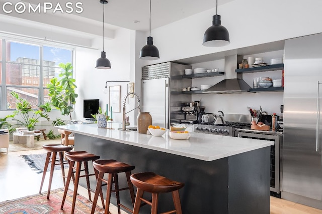 kitchen with range, island exhaust hood, built in refrigerator, and decorative light fixtures