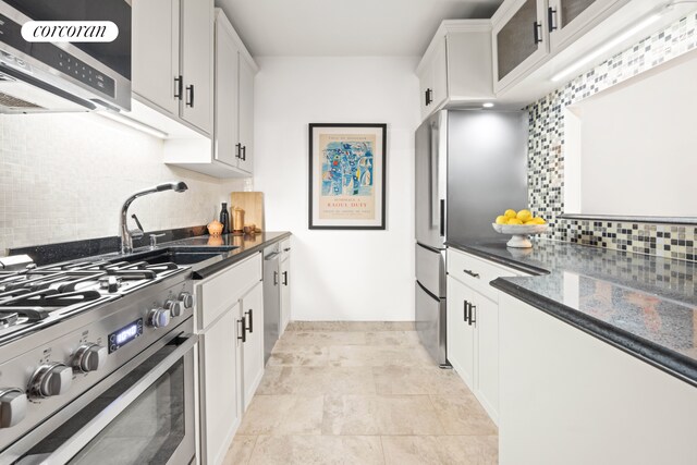 kitchen with appliances with stainless steel finishes, white cabinetry, sink, dark stone countertops, and decorative backsplash