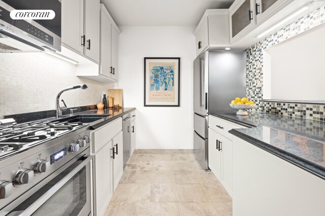 kitchen with appliances with stainless steel finishes, tasteful backsplash, a sink, and white cabinetry