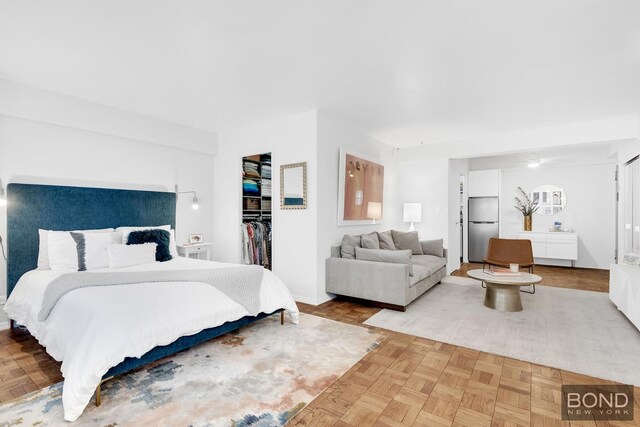 bedroom featuring light parquet flooring, stainless steel built in refrigerator, a spacious closet, and a closet