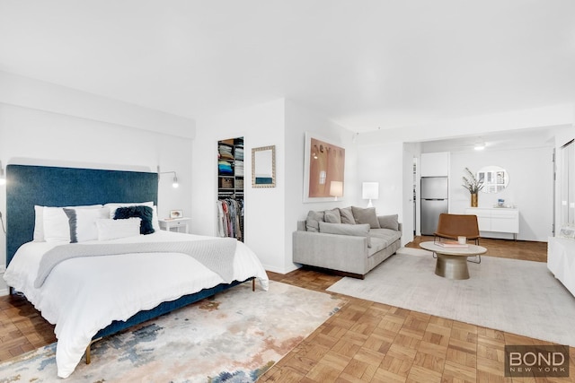 bedroom featuring a walk in closet, a closet, and freestanding refrigerator