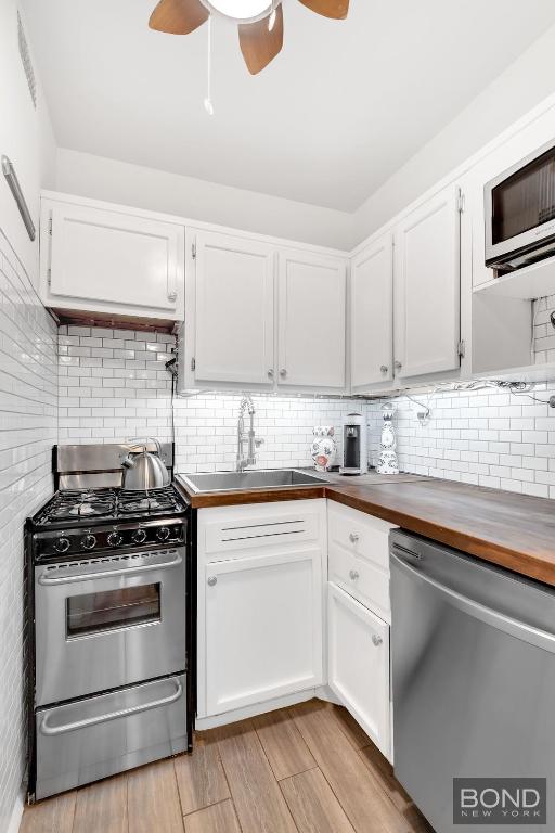 kitchen featuring white cabinetry, wood counters, and stainless steel appliances