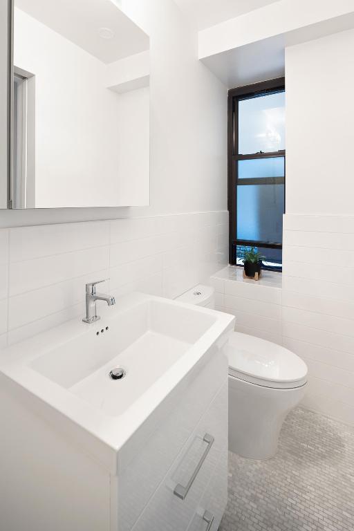 half bath with tile patterned flooring, tile walls, vanity, and toilet