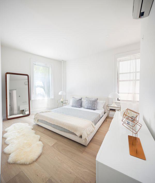 bedroom with light wood-style flooring and an AC wall unit