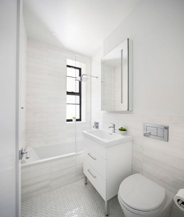 bathroom with toilet, tile patterned flooring, tile walls, and vanity