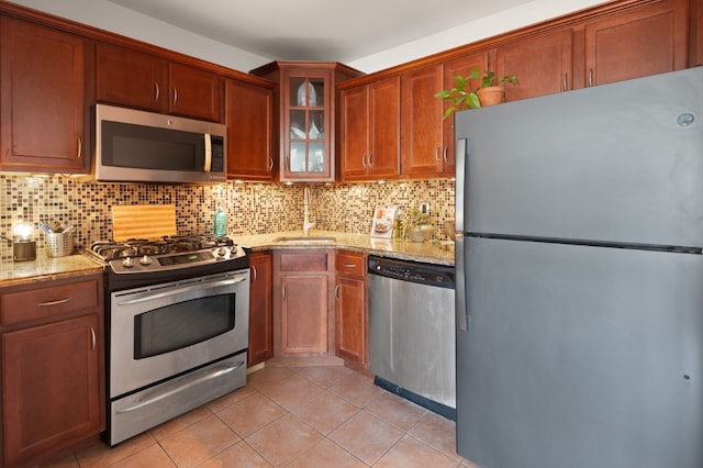 kitchen featuring stainless steel appliances, light stone countertops, sink, and decorative backsplash