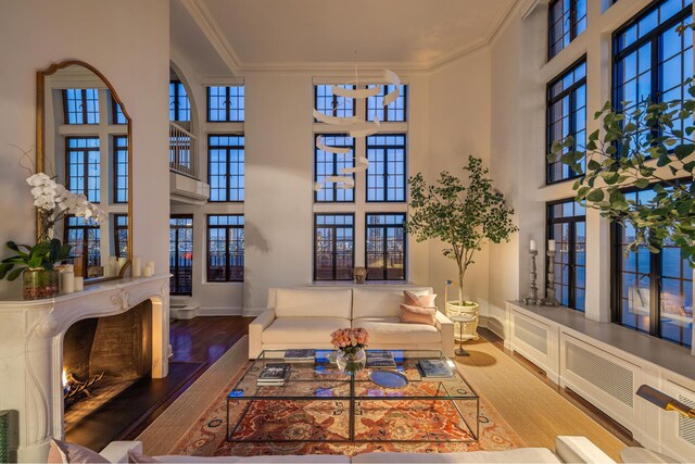 living area featuring a warm lit fireplace, ornamental molding, hardwood / wood-style flooring, and baseboards