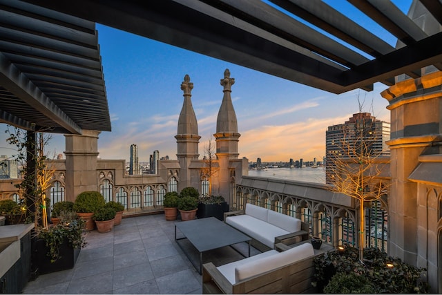 patio terrace at dusk featuring a pergola, an outdoor hangout area, and a city view