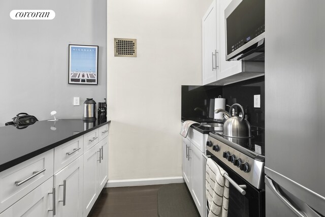 kitchen featuring appliances with stainless steel finishes, sink, white cabinets, decorative backsplash, and dark wood-type flooring