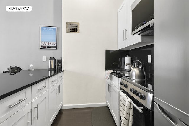 kitchen featuring baseboards, visible vents, dark wood-type flooring, white cabinets, and appliances with stainless steel finishes