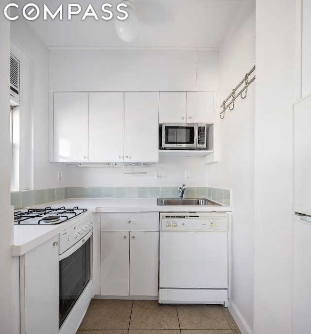 kitchen with sink, white appliances, white cabinetry, and light tile patterned flooring