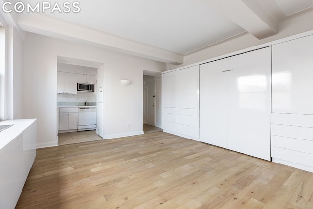 interior space featuring beam ceiling, a closet, ensuite bathroom, and light hardwood / wood-style floors