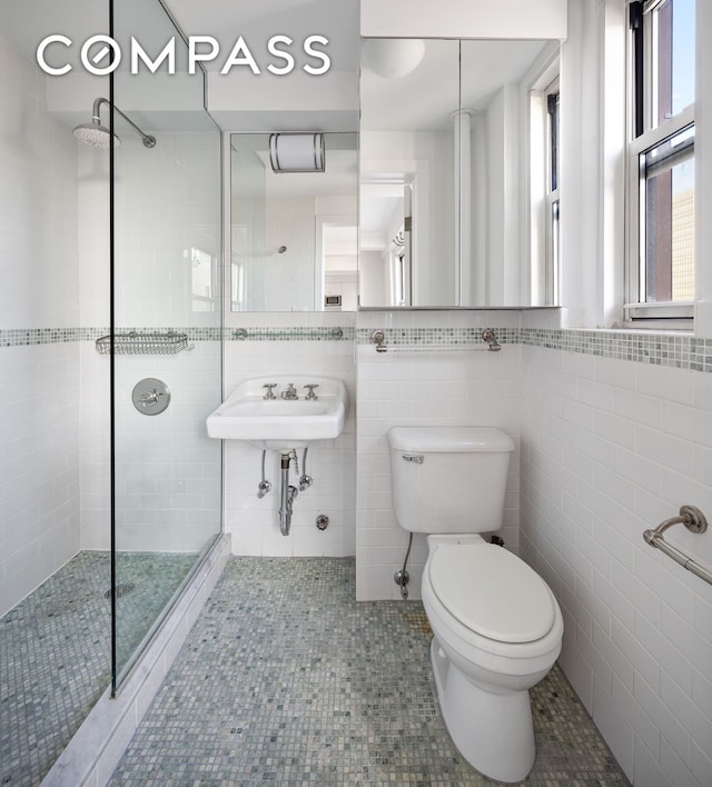 bathroom featuring a tile shower, tile walls, toilet, and tile patterned floors