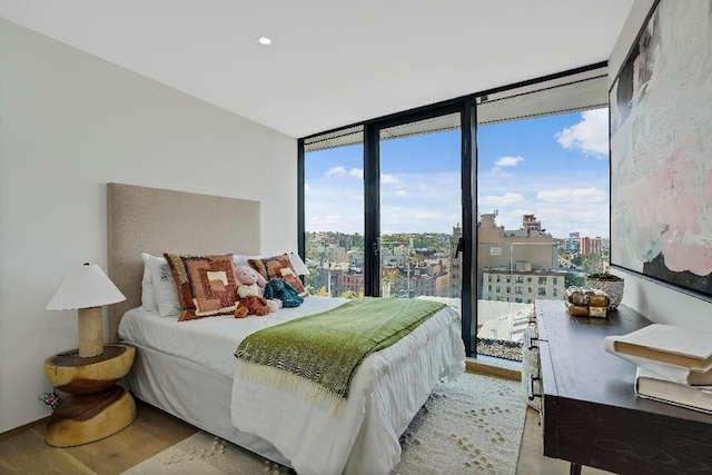 bedroom with a wall of windows and light hardwood / wood-style floors