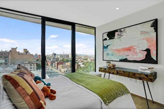 bedroom featuring multiple windows, hardwood / wood-style flooring, and a wall of windows