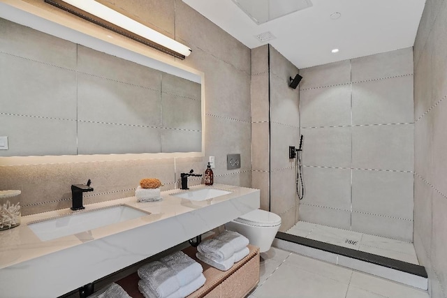 bathroom with vanity, tiled shower, tile walls, and toilet