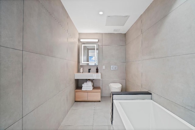 bathroom featuring tile patterned floors, toilet, sink, tile walls, and a bath