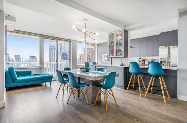 dining area featuring track lighting, an inviting chandelier, a city view, and wood finished floors