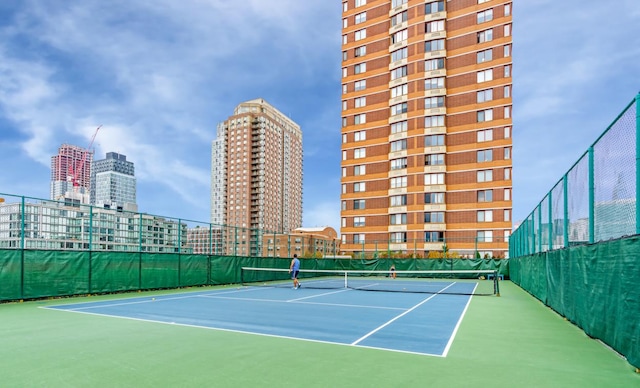 view of tennis court featuring a view of city, community basketball court, and fence