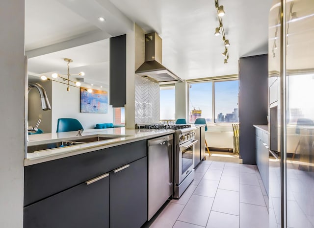kitchen featuring stainless steel appliances, light countertops, a sink, wall chimney exhaust hood, and decorative backsplash