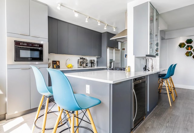 kitchen with oven, beverage cooler, a kitchen bar, rail lighting, and a peninsula