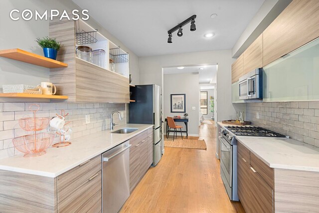 kitchen featuring decorative backsplash, appliances with stainless steel finishes, sink, and light hardwood / wood-style floors