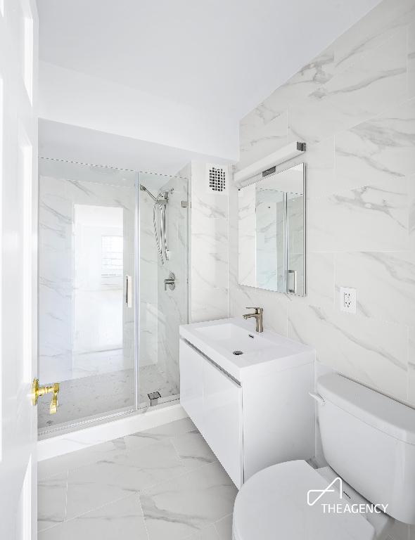 bathroom featuring a marble finish shower, visible vents, toilet, marble finish floor, and vanity