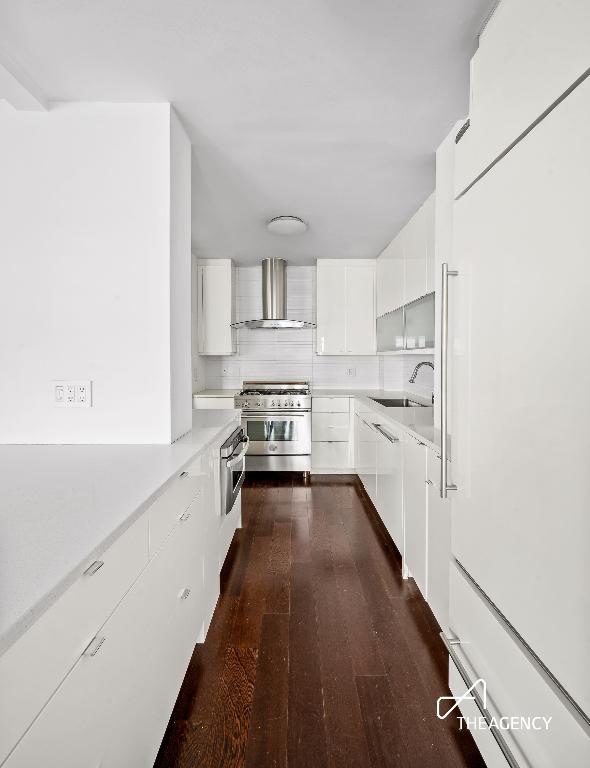 kitchen featuring wall chimney exhaust hood, white cabinetry, tasteful backsplash, dark hardwood / wood-style flooring, and high end stainless steel range oven