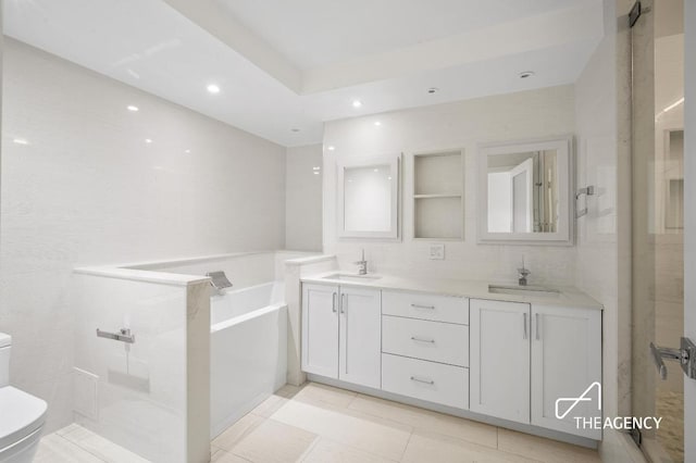 bathroom with a bath, double vanity, a sink, and toilet