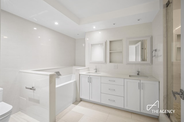 bathroom featuring a sink, a garden tub, toilet, and double vanity