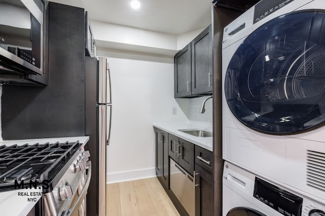 kitchen with sink, light hardwood / wood-style flooring, stainless steel appliances, stacked washer / dryer, and decorative backsplash