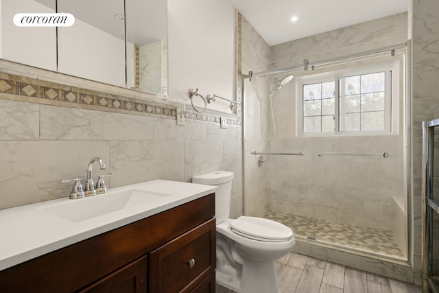 full bath with toilet, a stall shower, tile walls, and vanity