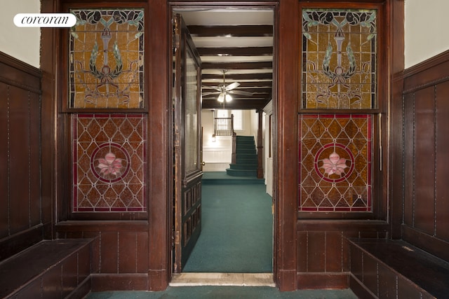 corridor with carpet floors, stairway, and beamed ceiling