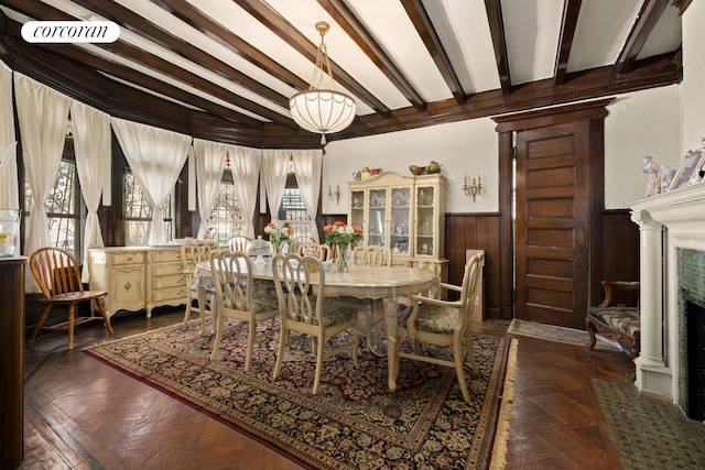 dining room featuring wainscoting, beamed ceiling, and wood walls