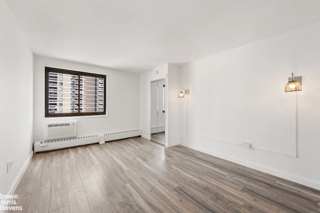 spare room with baseboard heating, hardwood / wood-style floors, and a wall mounted air conditioner