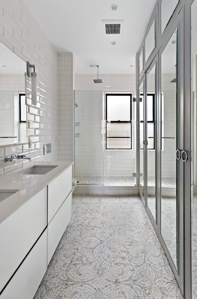 full bathroom featuring tile walls, shower / bath combination with glass door, vanity, toilet, and tile patterned floors