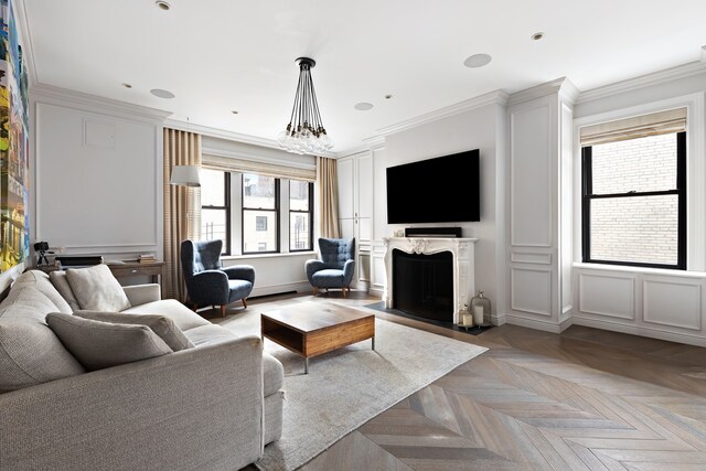 living room featuring an inviting chandelier, a high end fireplace, ornamental molding, and light parquet floors