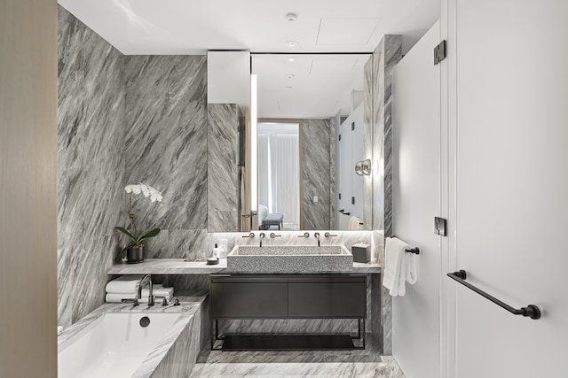 bathroom with a relaxing tiled tub, vanity, and tile walls